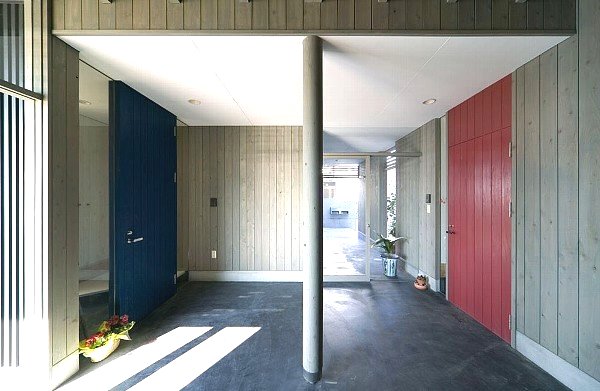 二世帯共用の玄関ポーチで８帖の広さがある．青が若い世代で赤が両親の玄関ドア．